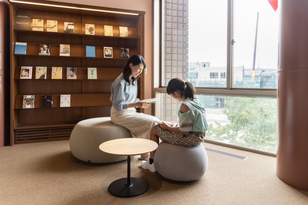 丸い椅子とテーブルが置かれた閲覧席 丸い椅子とテーブルが置かれた閲覧席で本を読む親子
