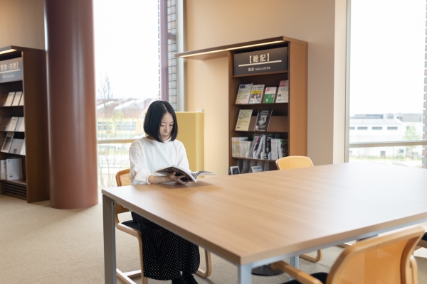 テーブルで本を読む女性 窓際の明るいテーブルで本を読む女性